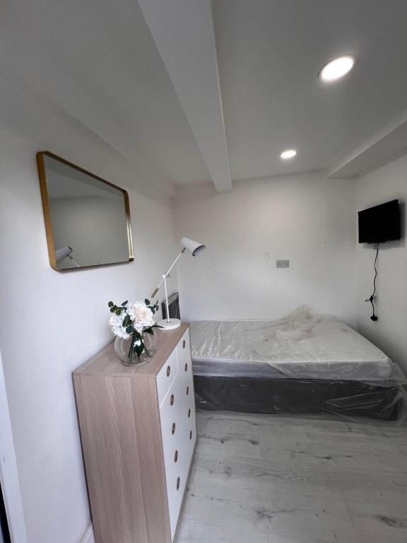 a bedroom with a bed and a dresser with a mirror at Ensuite Box Room in Corby NN17 in Rockingham