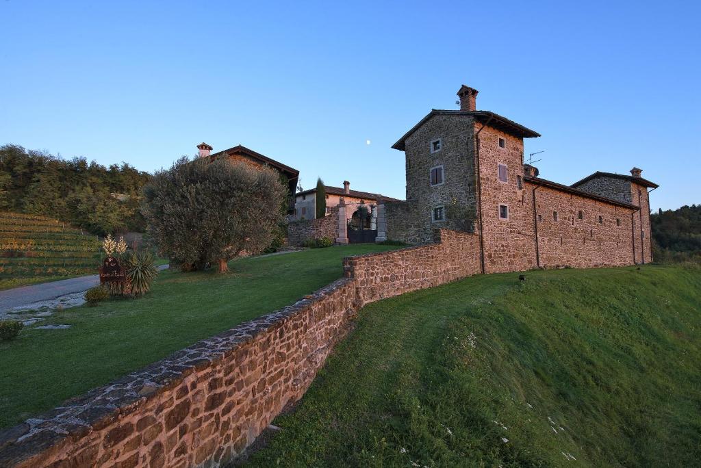 an old brick building on a hill with a wall at Agriturismo Ronchi Di Sant'Egidio in Manzano