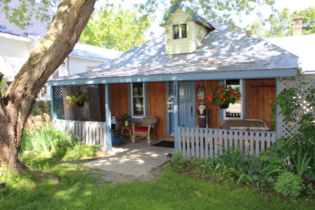 una piccola casa con portico e recinzione bianca di Spry Church Cozy Cottage a Lion's Head