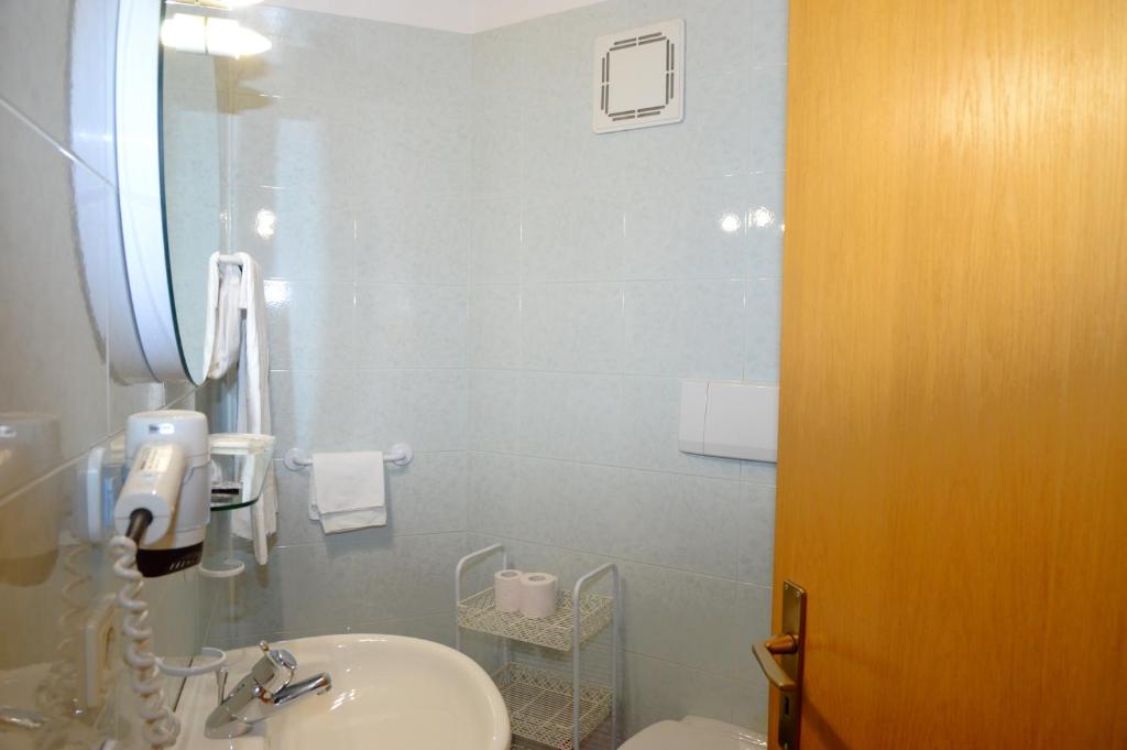 a bathroom with a sink and a toilet and a mirror at Residence Granvara in Ortisei