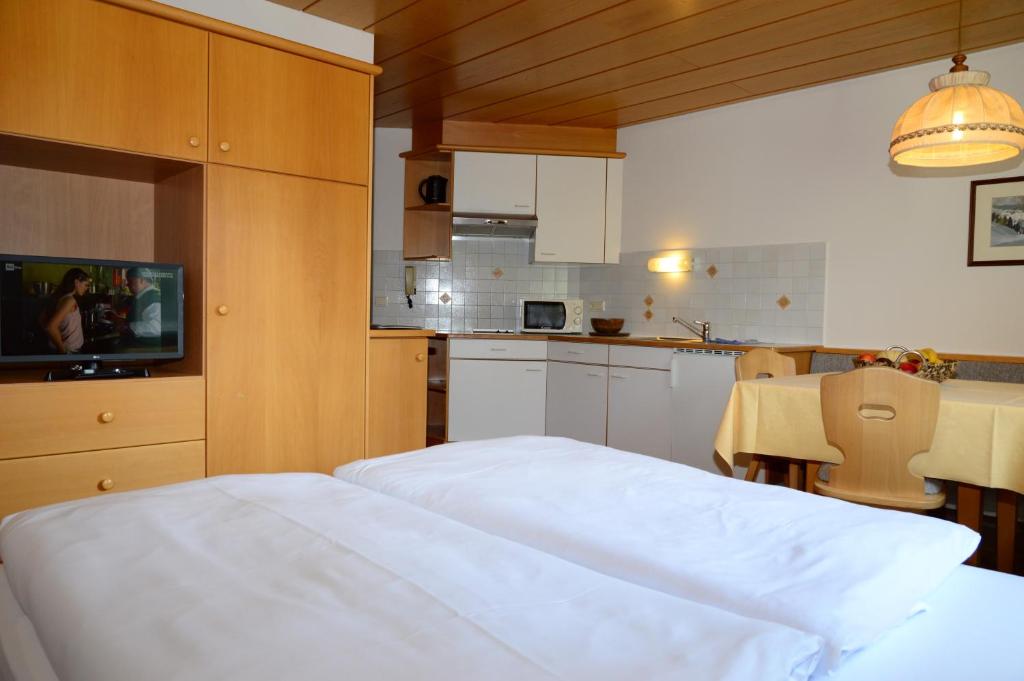 a bedroom with a white bed and a kitchen at Residence Granvara in Ortisei