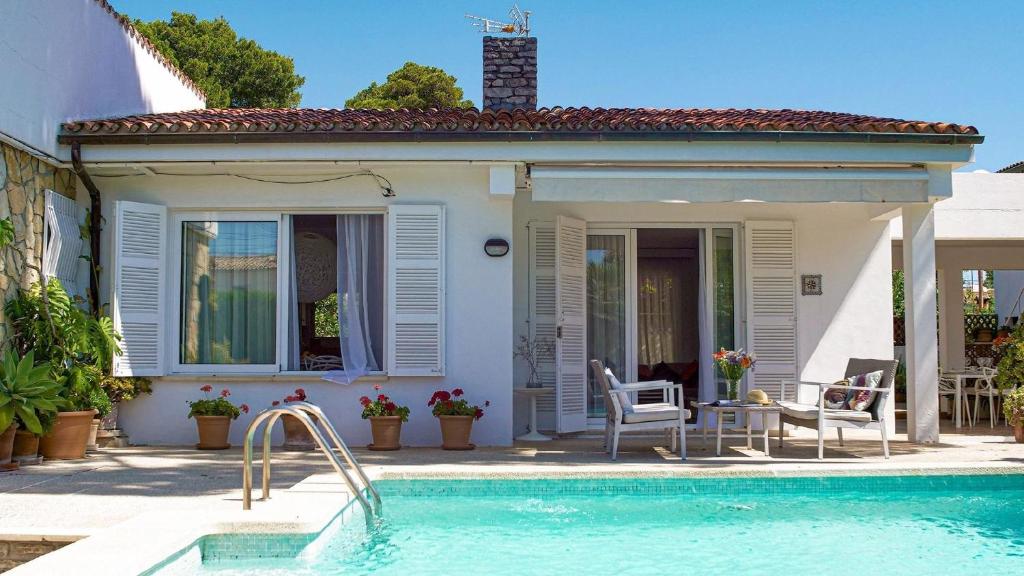 a house with a swimming pool in front of a house at Landhaus mit Garten, Sonnenterrasse sowie überdachter Terrasse und Pool in Strandnähe in Cala Ratjada