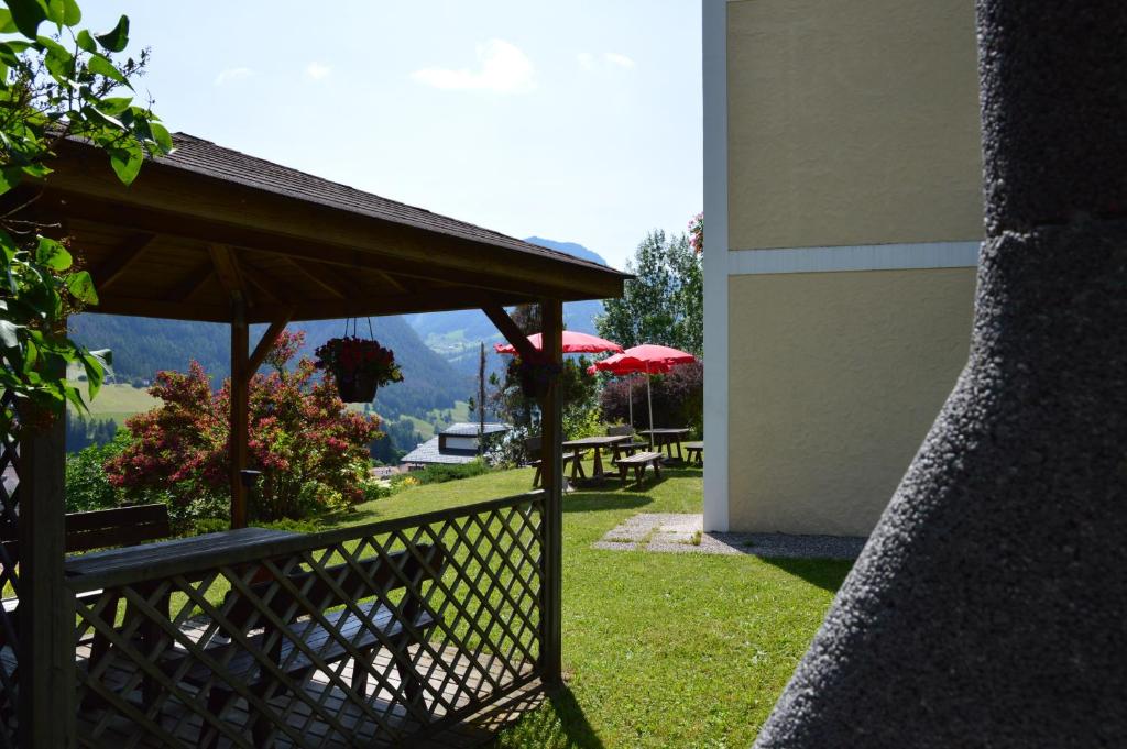 a patio with benches and umbrellas and a table at Residence Granvara in Ortisei