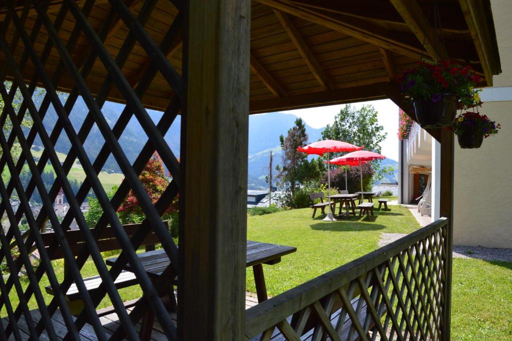 a porch with picnic tables and red umbrellas at Residence Granvara in Ortisei