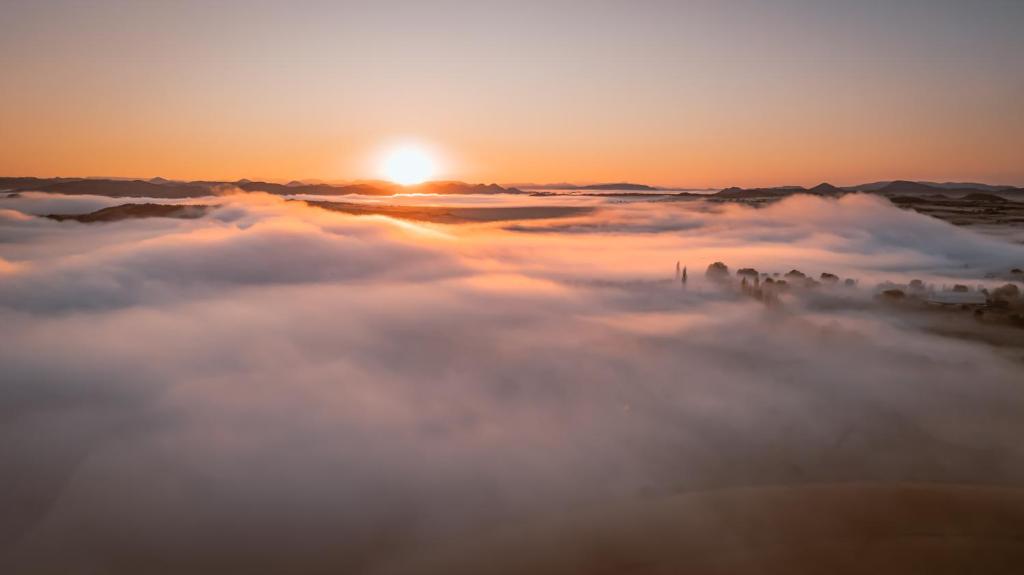 a view of the sun rising above a sea of clouds at Tzamenkomst River Lodge in Colesberg