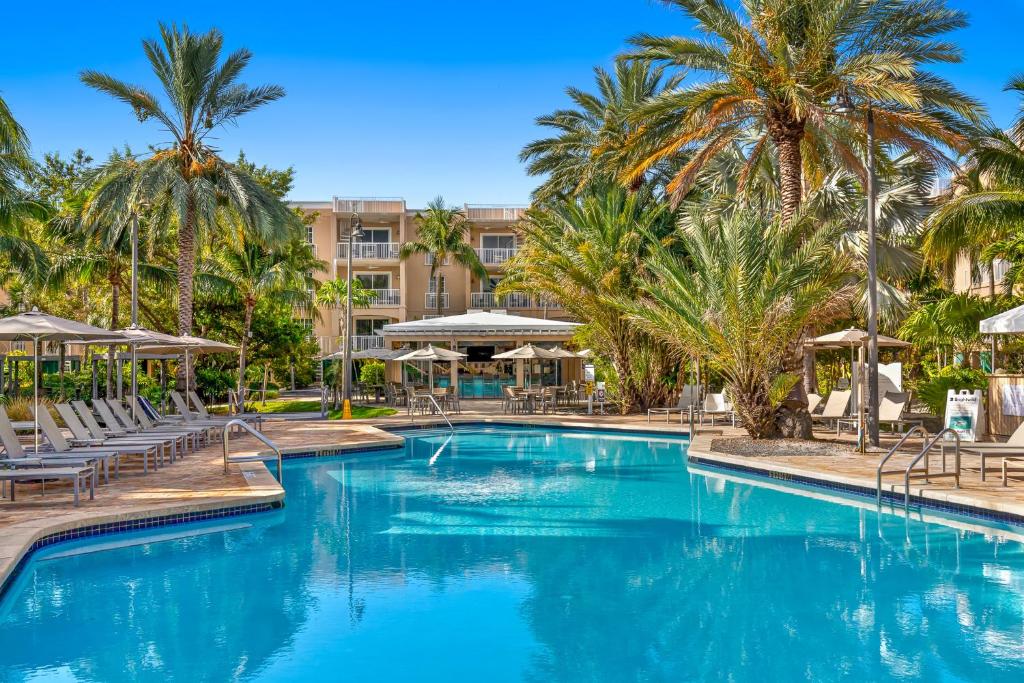 einen Pool mit Stühlen und Palmen in einem Resort in der Unterkunft Beachside Resort &amp; Residences in Key West