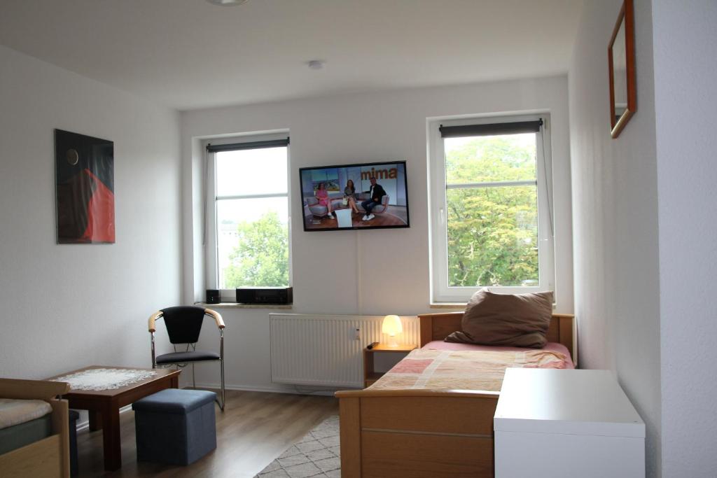 a bedroom with a bed and a desk and two windows at Pension963 in Crimmitschau