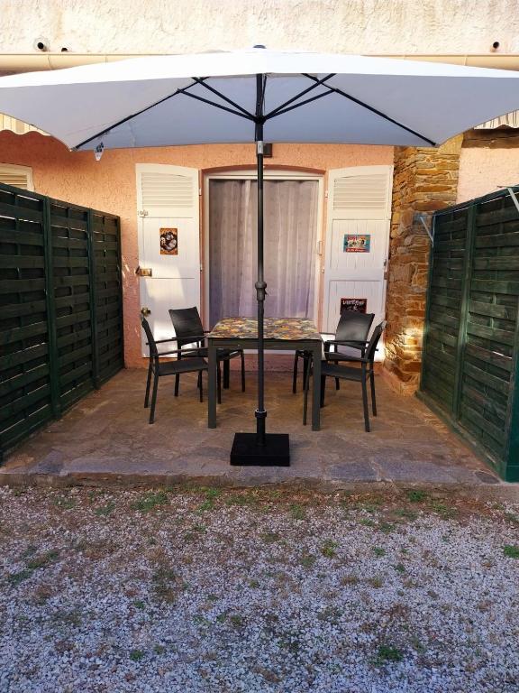 - une table et des chaises sous un parasol sur la terrasse dans l'établissement Prélude Beach, à Bormes-les-Mimosas