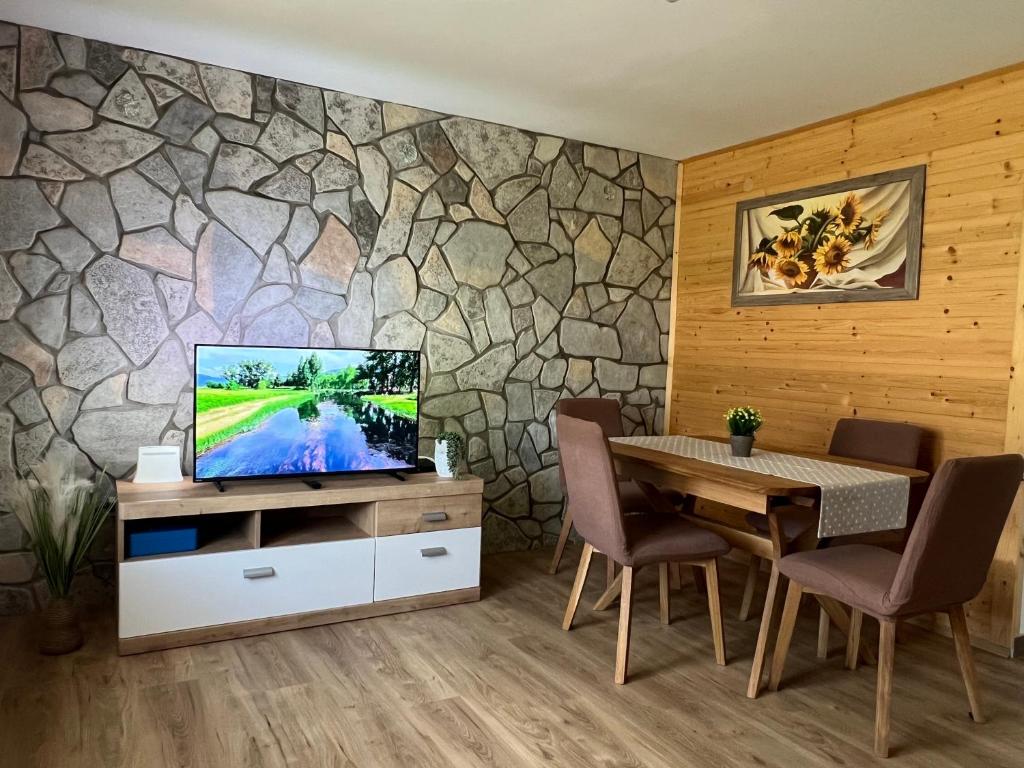 a dining room with a tv and a stone wall at Zen Den apartments in Otočac