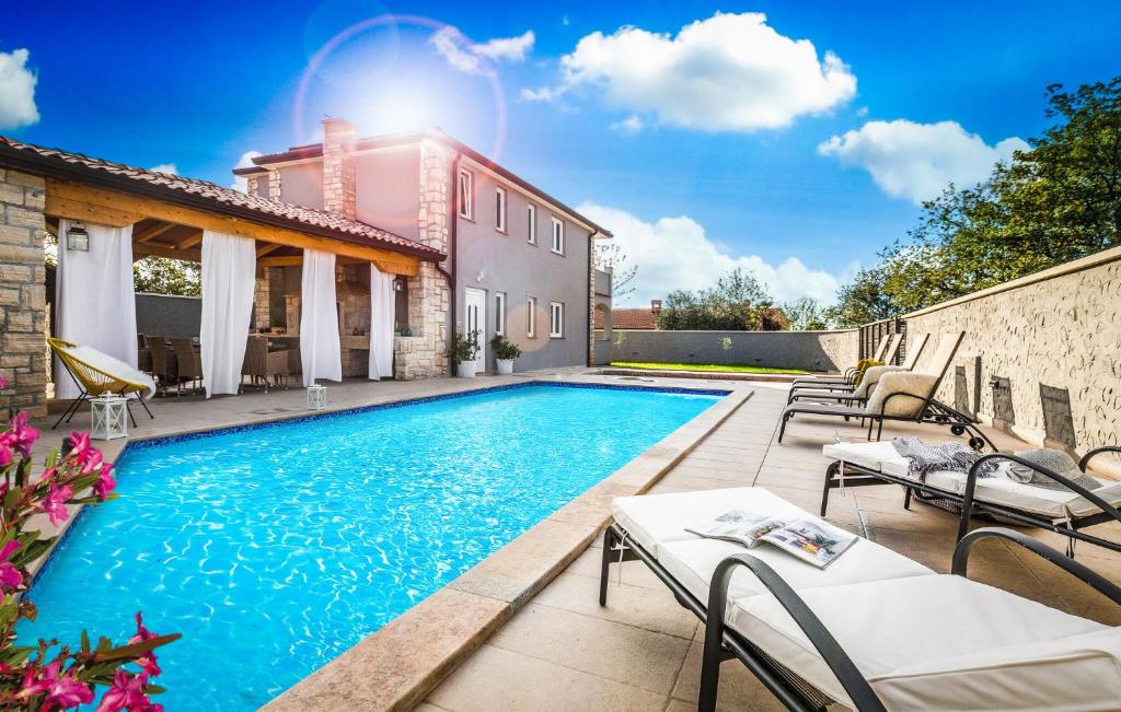 a swimming pool with patio furniture and a house at 4 Bedroom Cozy Home In Mihatovici in Rošini