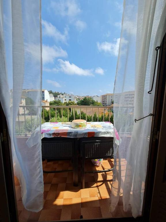 d'une fenêtre donnant sur un balcon avec une table. dans l'établissement Les Lauriers, à Saint-Raphaël