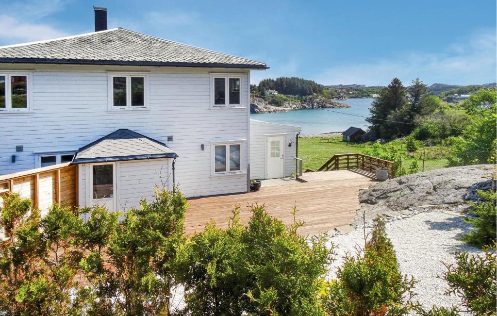 a house with a wooden deck next to a body of water at Cozy Home In Hellvik With Wifi in Hellvik