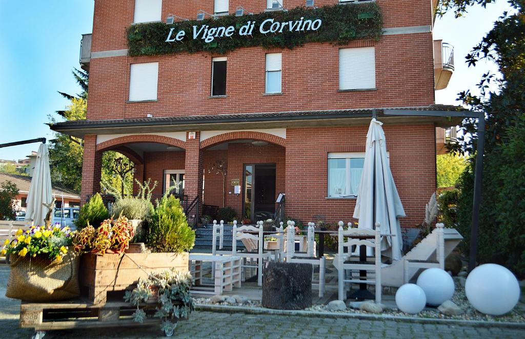 a building with chairs and umbrellas in front of it at Hotel Le Vigne di Corvino in Casteggio