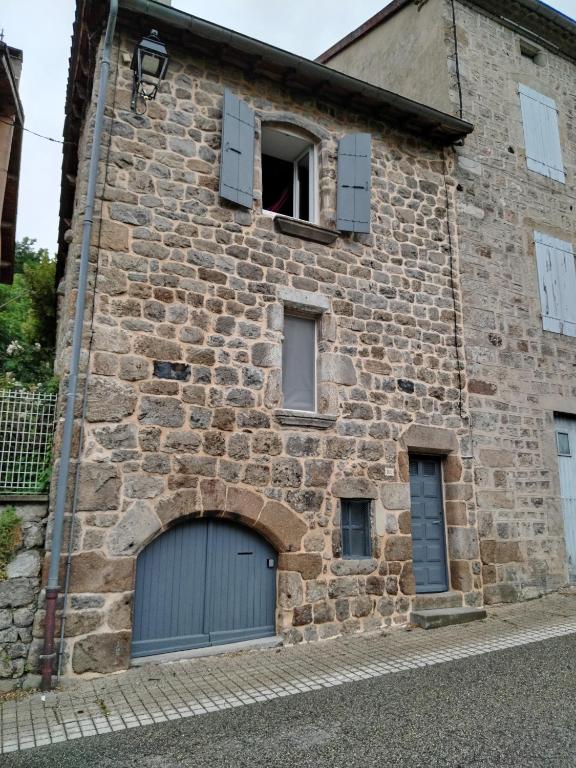 un ancien bâtiment en pierre avec un garage dans l'établissement Maison de Madeleine, à Montpezat-sous-Bauzon