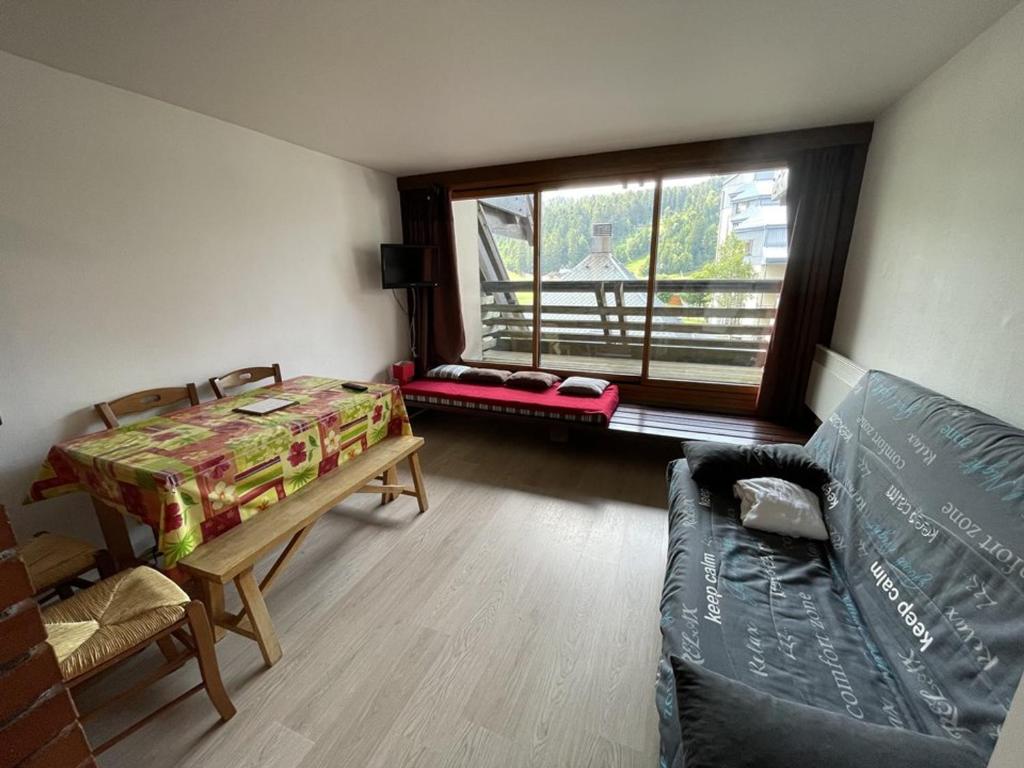 un salon avec un canapé et une fenêtre dans l'établissement Charmant studio avec balcon, au pied des pistes et commerces - FR-1-787-24, à Laveissière