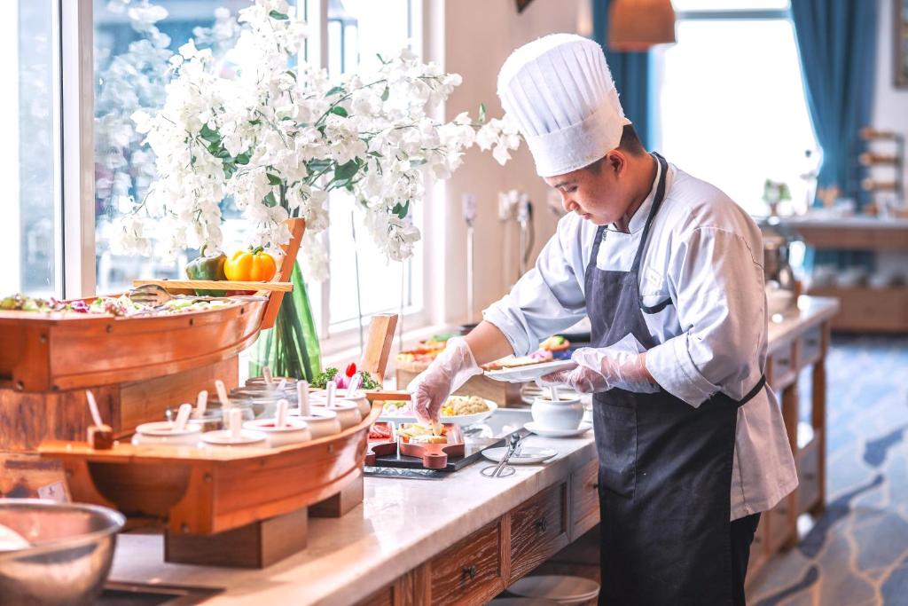 A chef prepares plated food at a bright restaurant buffet counter.