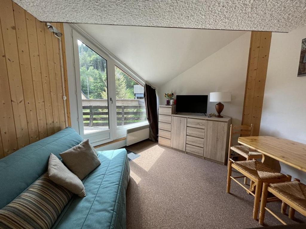 un salon avec un canapé bleu et une télévision dans l'établissement Studio avec balcon au centre station, proche pistes et patinoire - FR-1-787-46, à Laveissière