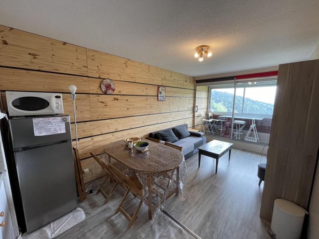 eine Küche und ein Wohnzimmer mit Kühlschrank und Tisch in der Unterkunft Appartement T2 cabine avec balcon, accès piste, parking, animaux bienvenus - FR-1-787-69 in Laveissière
