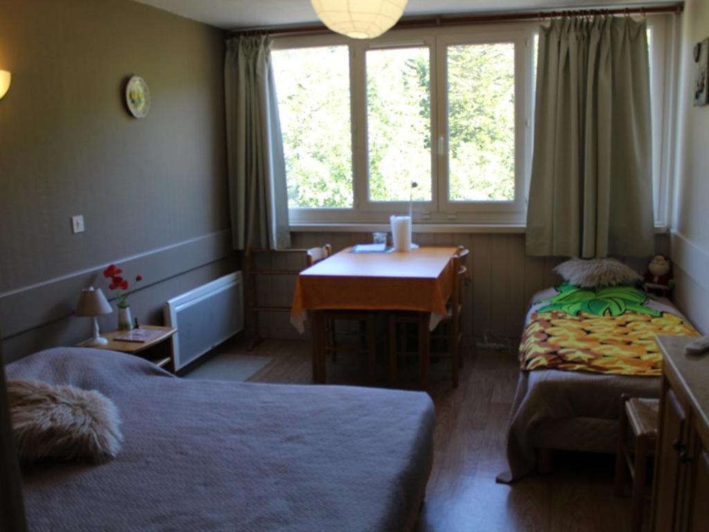 une chambre avec deux lits et un bureau et une fenêtre dans l'établissement Studio cosy 2/3 pers, 200m pistes, wifi, parking, animaux ok - FR-1-787-49, à Laveissière