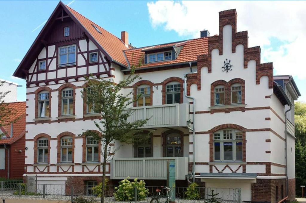 un grand bâtiment blanc avec une horloge. dans l'établissement Välkommen, à Stralsund