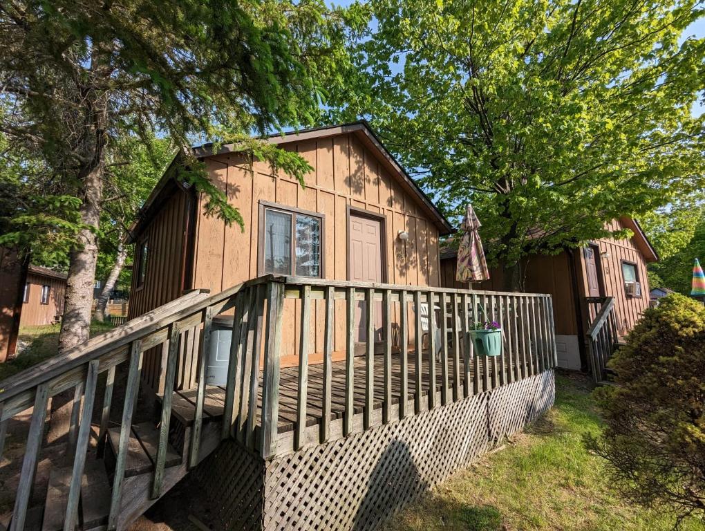 una casa in legno con portico e recinzione di Tiny Wood Cottage 14 a Wasaga Beach