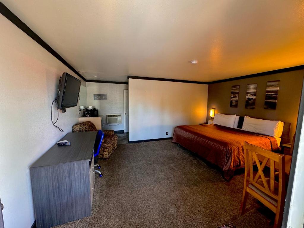 a room with a bed and a desk and a television at Cascade Lodge in Bend