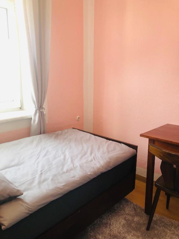 a bed in a room with a window and a table at Holmes Café & Pension in Engelhartszell