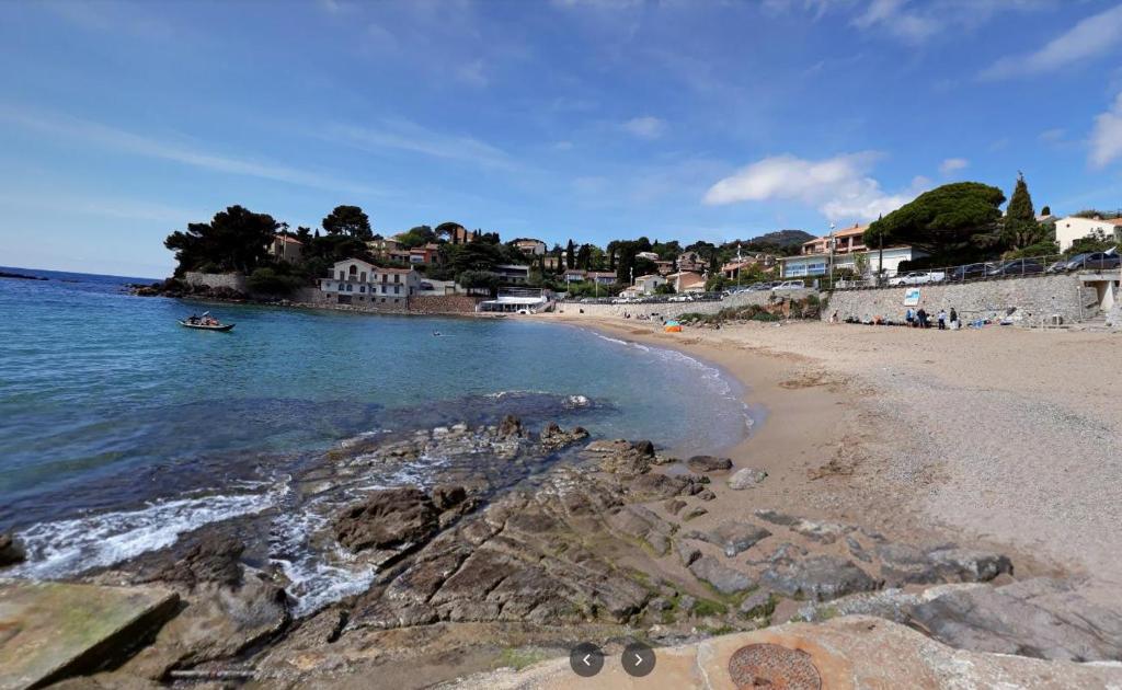 - une vue sur la plage avec un bateau dans l'eau dans l'établissement Appartements avec terrasses, plancha, wifi, climatisation ,proche de la mer, au Pradet