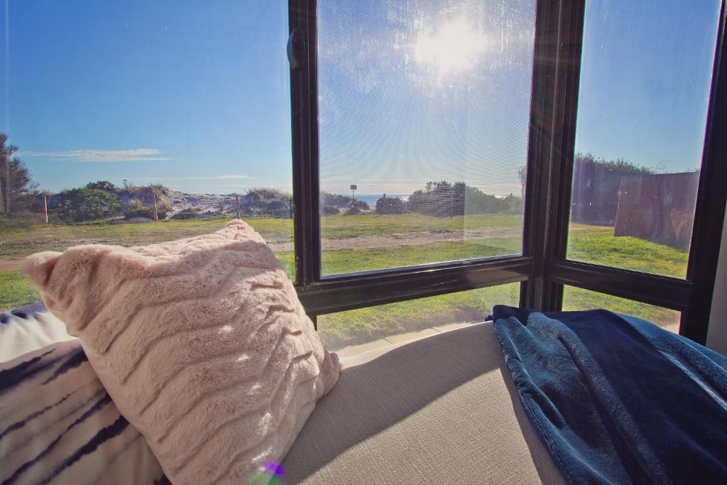 Port AdelaideBeach Stayz Semaphore Three Bedroom Apartment的枕头坐在窗前的沙发上