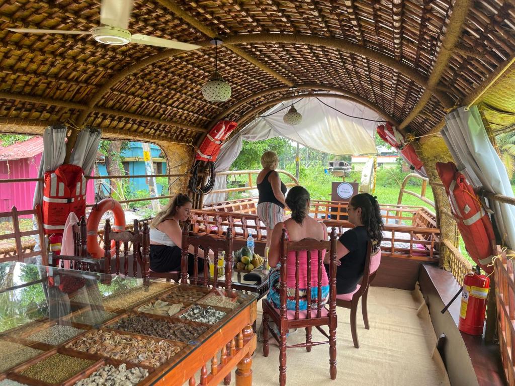 a group of people sitting at a table in a bus at Thara's Houseboat in Alleppey