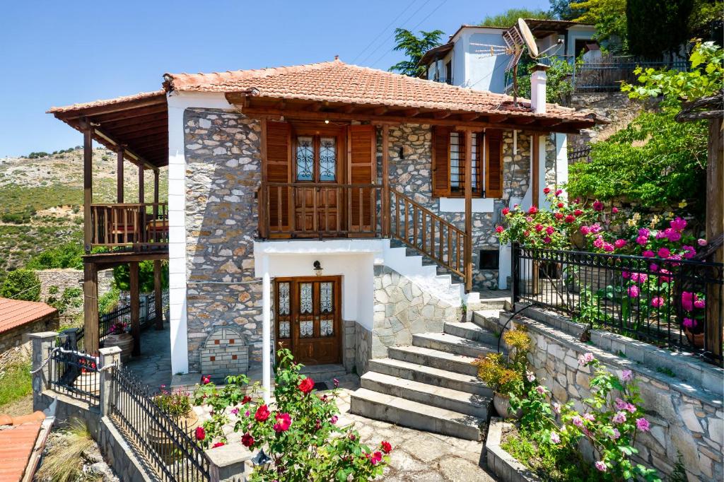 a small stone house with flowers in front of it at Etherio House in Skala Sotiros