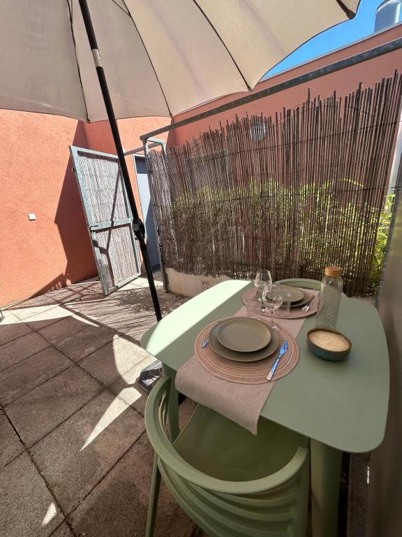 une table avec des assiettes, des verres et un parapluie dans l'établissement Fleur de Soleil, à Arles