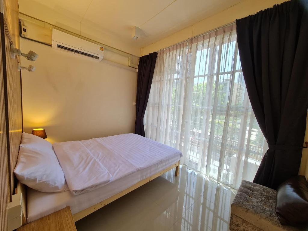 a bedroom with a bed and a large window at De Chalet in Bangkok