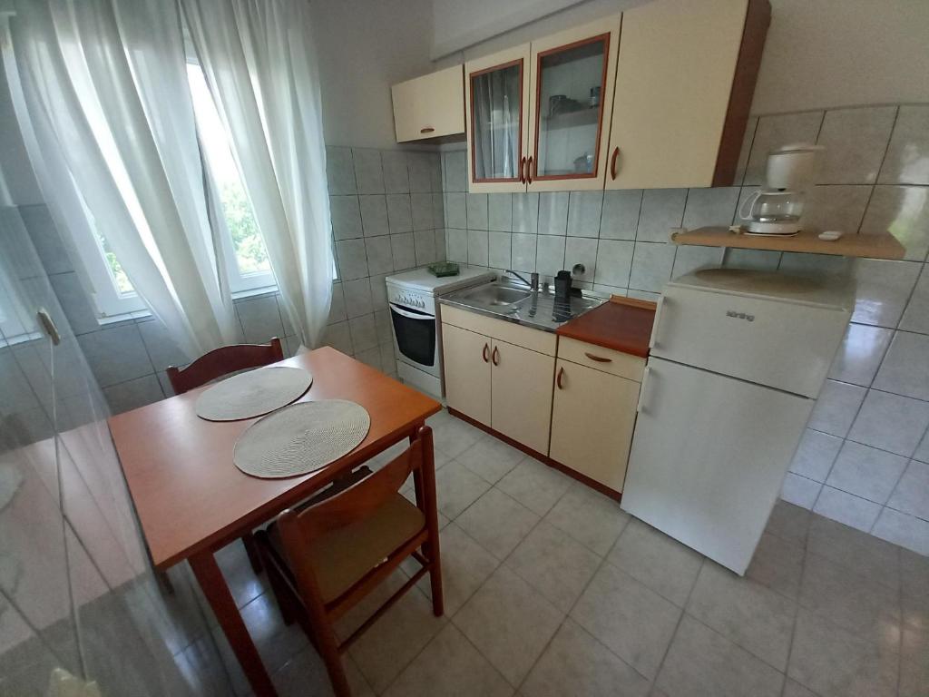 eine kleine Küche mit einem Tisch und einem weißen Kühlschrank in der Unterkunft Peša Holiday Apartments in Zaton