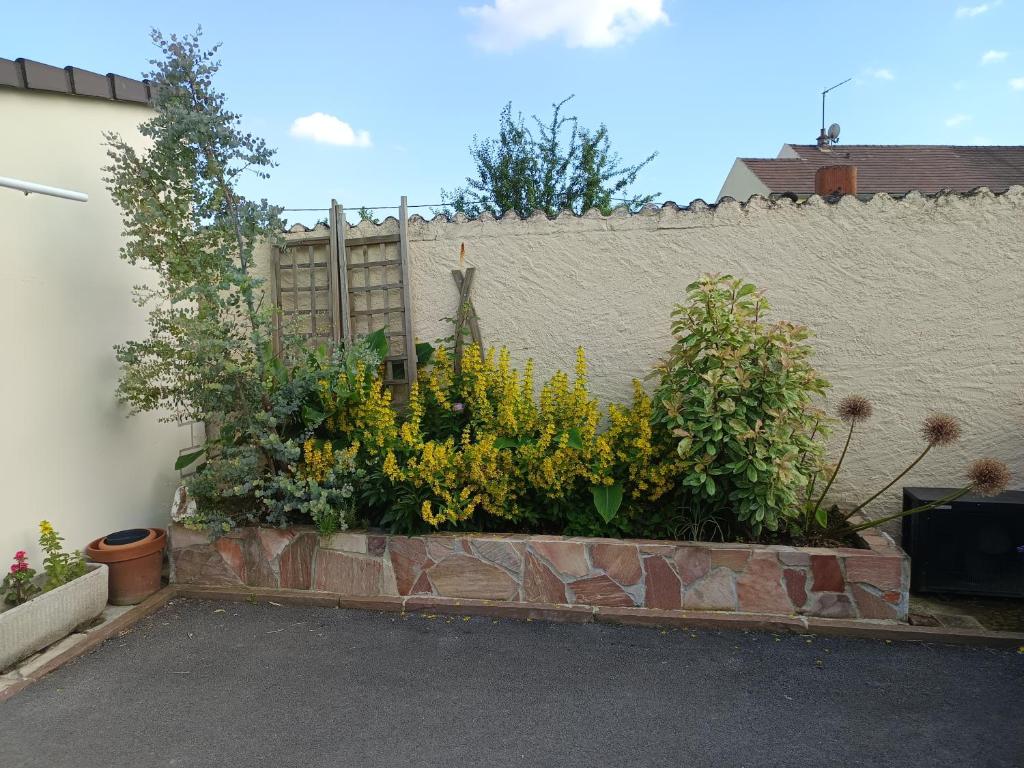 un jardín con flores frente a una pared en jolie maison neuve - malisone -, en Pont-Sainte-Maxence