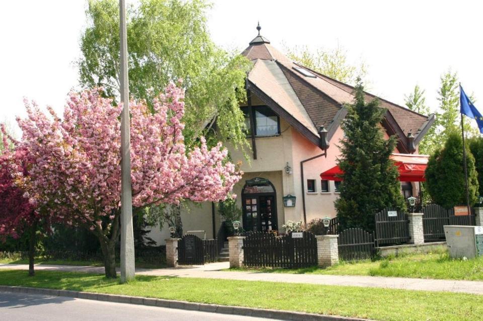 una casa con un albero da fiore di fronte di Kocsis Panzió és Étterem a Komárom