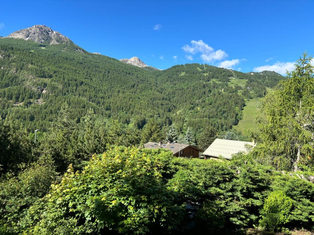 une maison dans une vallée avec des montagnes en arrière-plan dans l'établissement Appartement bonne situation ,exposition, à Saint-Chaffrey