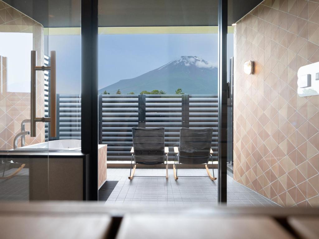 a bathroom with two chairs and a view of a mountain at Mt Fuji View and Private Sauna Ryokan Shizuku in Yamanakako