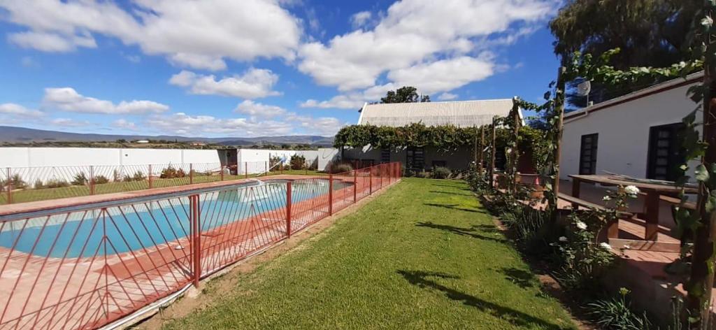 a swimming pool with a fence next to a house at Farmhouse Guestrooms in Calitzdorp
