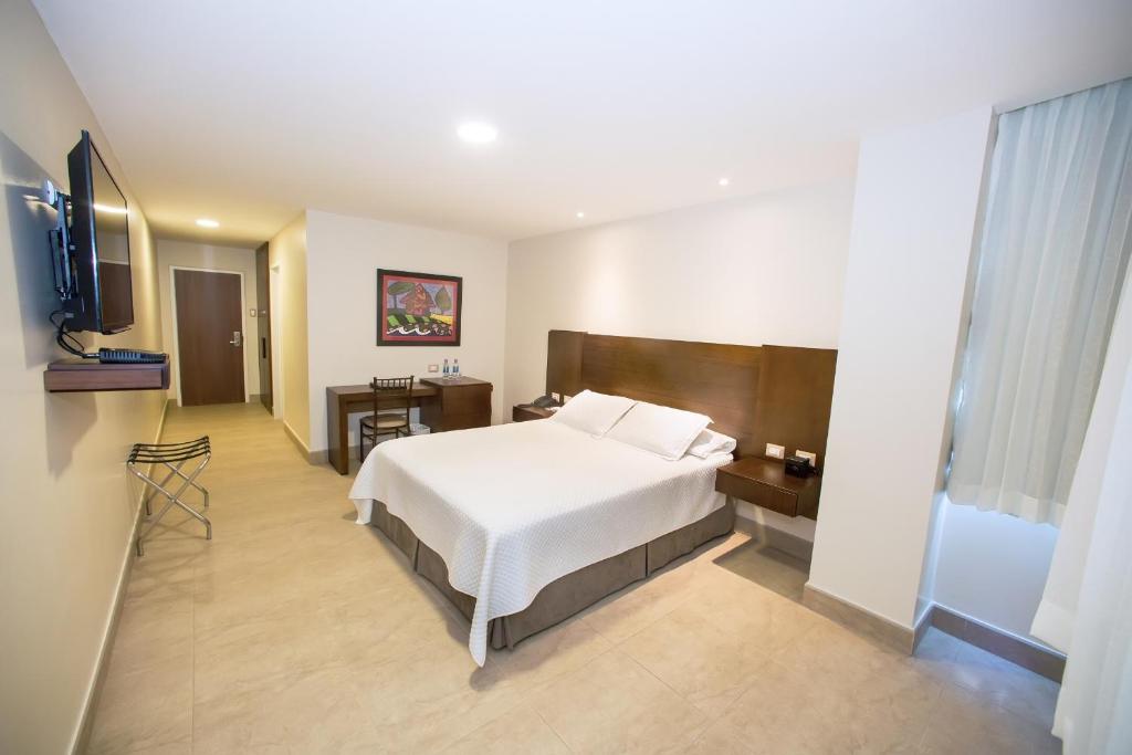 Habitación de hotel con cama y TV en Hotel Marcelius, en Guayaquil
