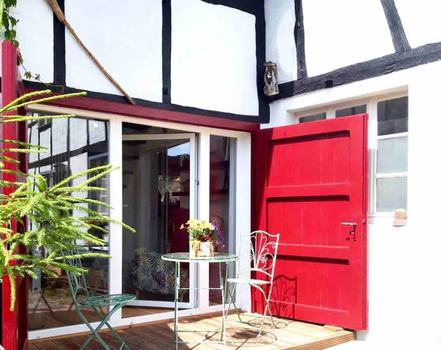 a red door on a house with a table at Eyes Ferienhaus im Nationalpark Eifel in Schleiden