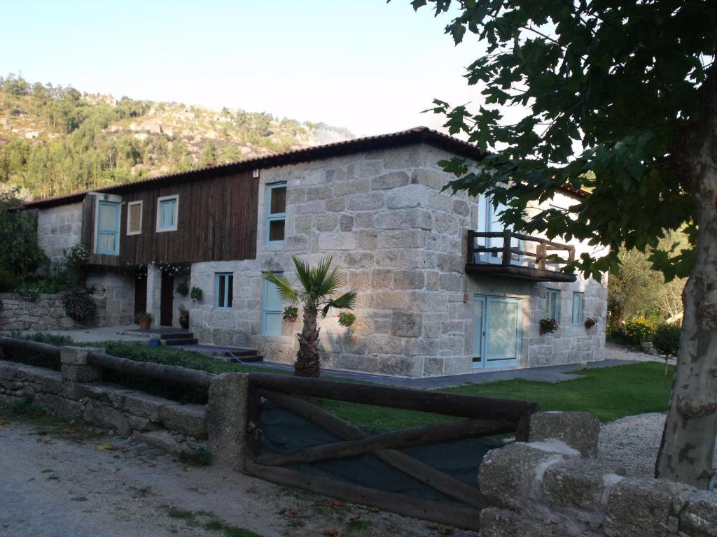 a stone house with a fence in front of it at Casa da Figueira in Póvoa de Lanhoso