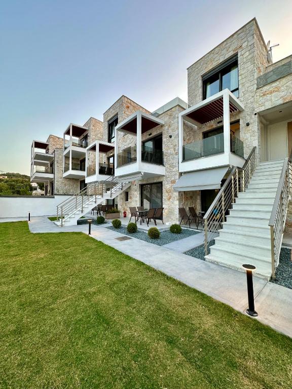 an exterior view of a building with stairs and grass at Rigas Boutique Rooms in Pefkochori