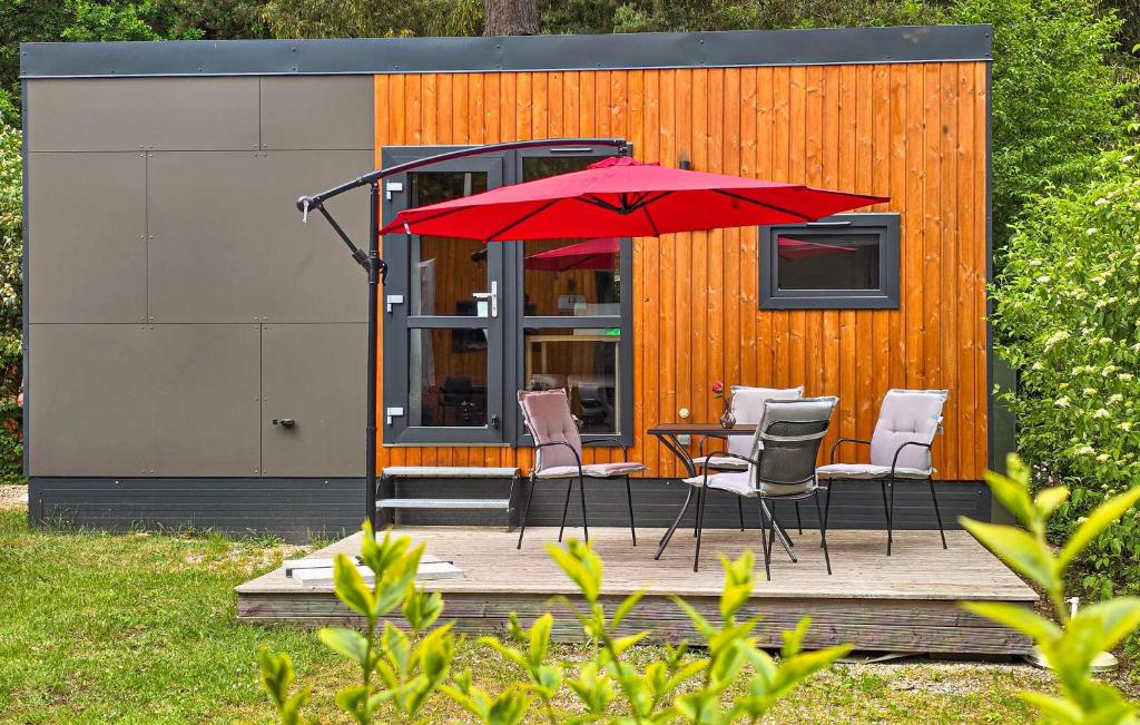 ein roter Sonnenschirm auf einer Terrasse mit Stühlen und einem Tisch in der Unterkunft Tiny Haus 74 Am Brombachsee in Pleinfeld