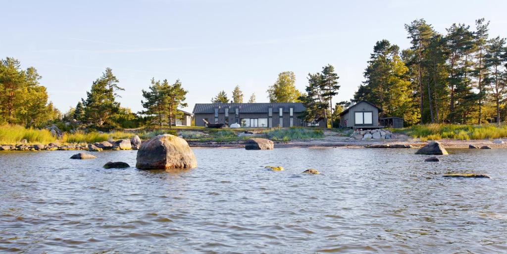 uma casa na margem de um lago com pedras na água em Kalaranna Holiday Home em Eisma