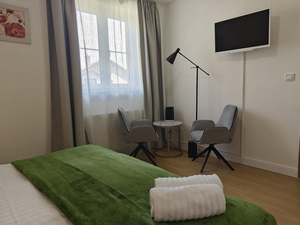 a bedroom with a bed with a television and chairs at Achilla Bed & Breakfast in Český Krumlov