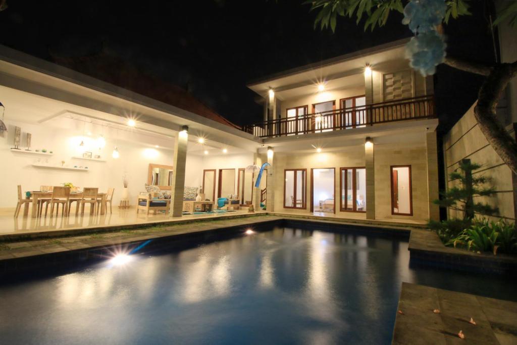 a swimming pool in front of a house at night at Villa Alam Biru in Sanur