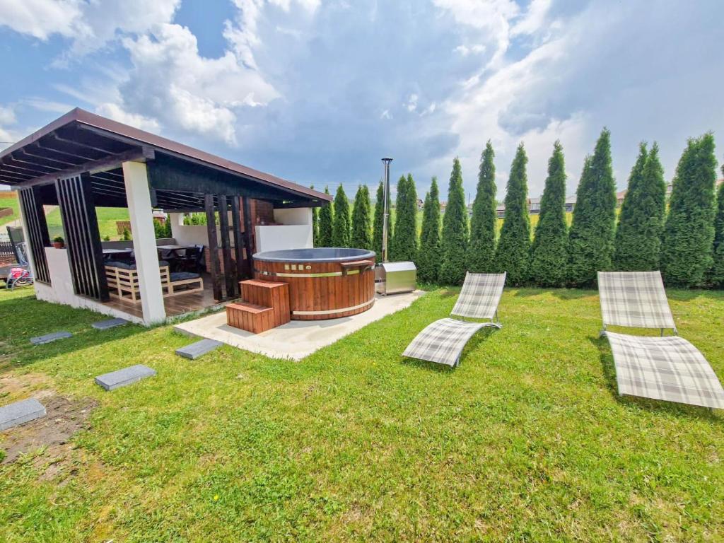 une cour arrière avec un gazebo, deux chaises et un barbecue dans l'établissement Natúr Vendégház, à Miercurea-Ciuc
