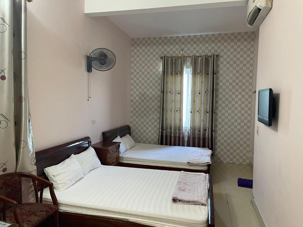 a small room with two beds and a tv at Nhà Nghỉ Long Lưu in Vinh