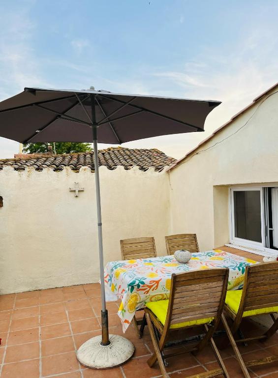 une table et des chaises avec un parasol sur une terrasse dans l'établissement Maison de village, à Peyriac-Minervois